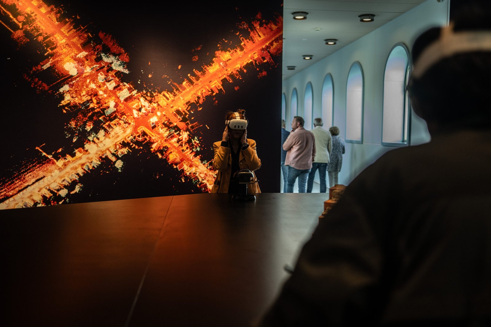 A visitor wearing a VR headset in front of a large orange LiDAR image at the Groninger Museum