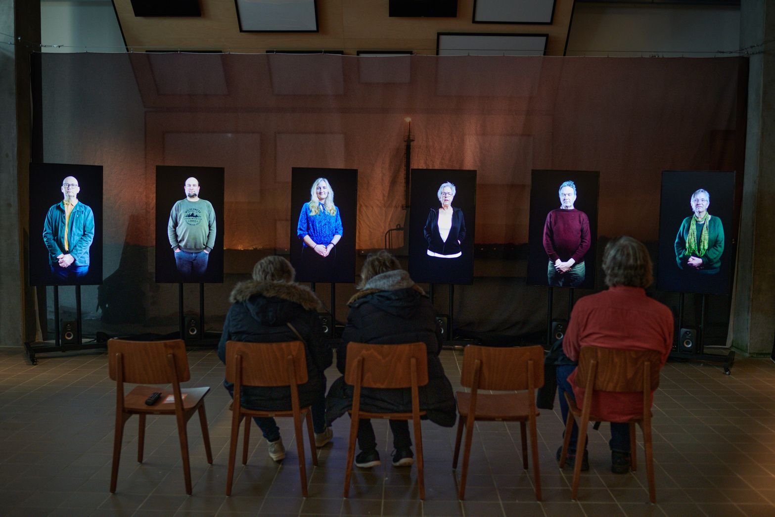 Visitors seated before the multi-screen portrait installation at Beeld & Geluid in The Hague