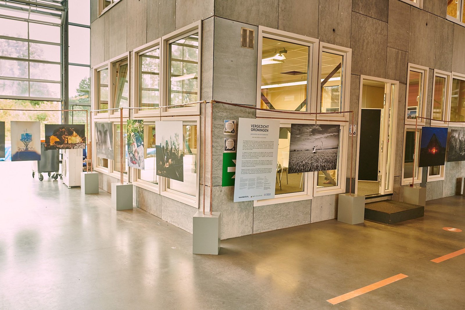 Vergezicht Groningen exhibition at Building G, with photographs displayed around a built house interior